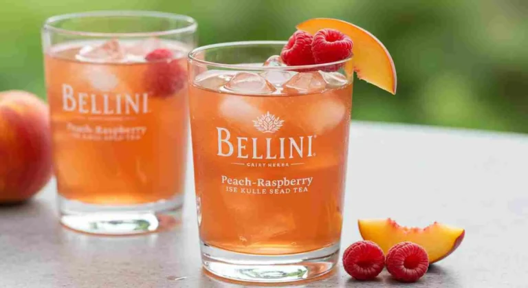 A glass of Bellini Peach-Raspberry Iced Tea with ice and a fruit garnish.